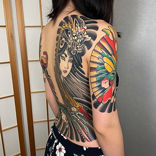 Photograph of a woman with a large, colorful Japanese-style tattoo on her back and right shoulder, featuring a detailed female face and vibrant floral designs,