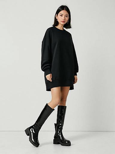 Woman in Oversized Black Sweatshirt Dress and Glossy Black Boots