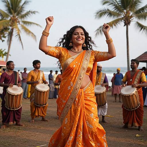 Photograph of a smiling Indian woman in an orange saree with gold embroidery, dancing with drummers in traditional attire, palm trees, and ocean in