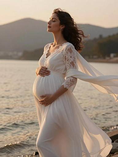 Pregnant Woman in Flowing White Maternity Dress by the Shore