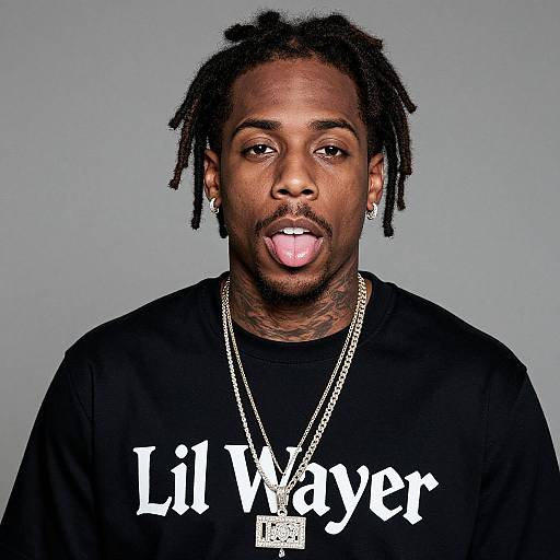 Photograph of a young Black man with dreadlocks, tongue sticking out, wearing a black shirt with 