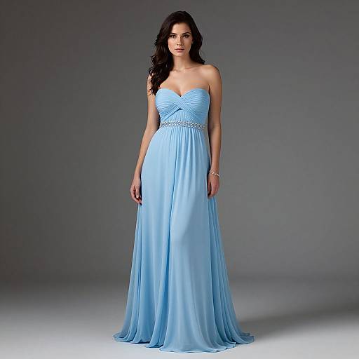 Photograph of a dark-haired woman in a strapless, light blue, floor-length gown with a beaded bodice, standing against a gray background