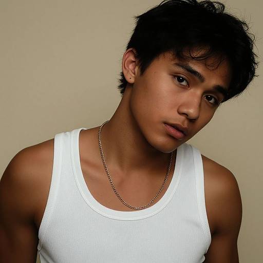 Photograph of a young Asian man with short, messy black hair, wearing a white ribbed tank top and a thin gold chain, against a plain