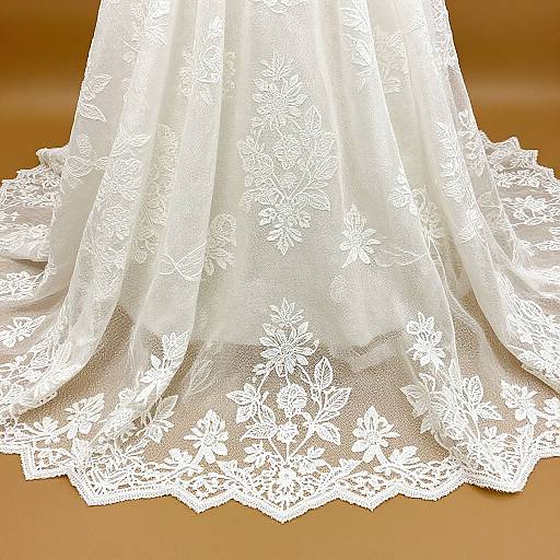 Photograph of an elegant white lace wedding dress skirt, featuring intricate floral patterns, with a wide, flowing hem and delicate texture.