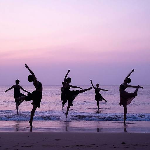Silhouetted dancers in graceful poses on a beach at sunset, with gentle waves and a purple-pink sky in the background.