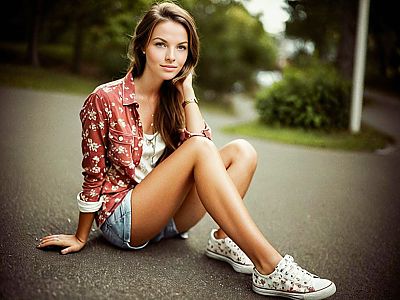 Stylish young woman in floral shirt and denim shorts