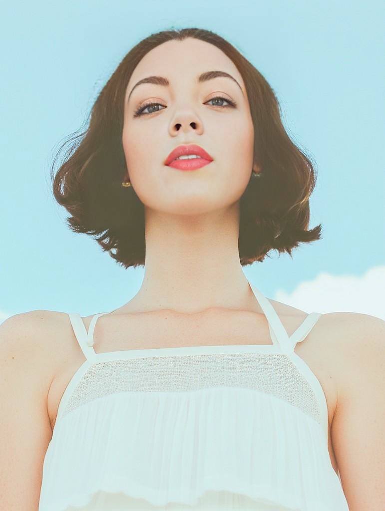 Confident Woman in White Top Against Blue Sky