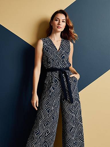 Stylish Woman in Abstract Patterned Navy Jumpsuit Against Geometric Background