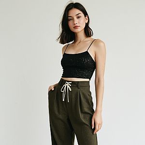 Contemporary Casual Woman in Shimmering Black Tank Top with Thin Straps and Olive Green Pants
