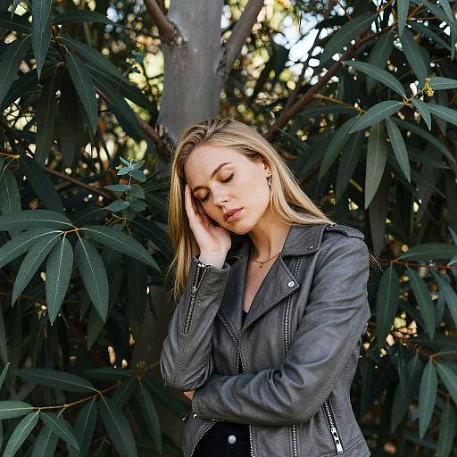 Serene Young Woman in Grey Leather Jacket Against Tropical Foliage