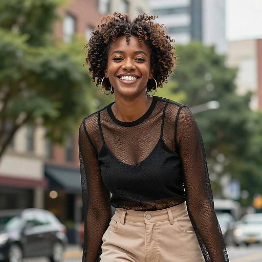 Smiling Young Woman in Stylish Black Mesh Top and Beige Pants in Urban Setting