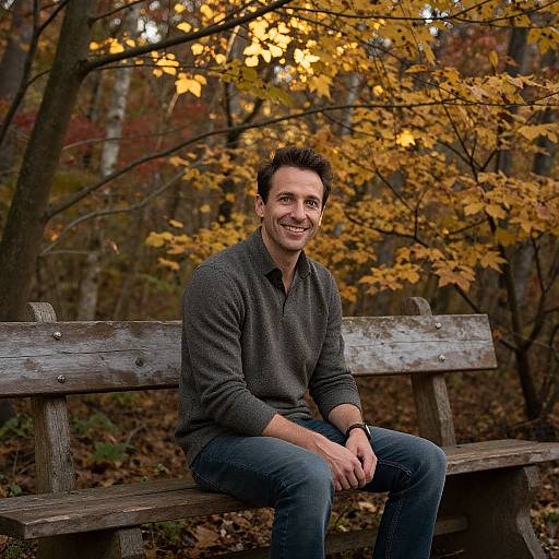 Man Sitting on Wooden Bench in Autumn Forest with Yellow Leaves