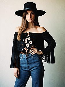 Young Woman in Boho Chic Outfit with Wide-Brimmed Hat and Fringe Jacket