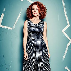 Red-Haired Woman in Navy Polka Dot Dress Against Abstract Teal Wall