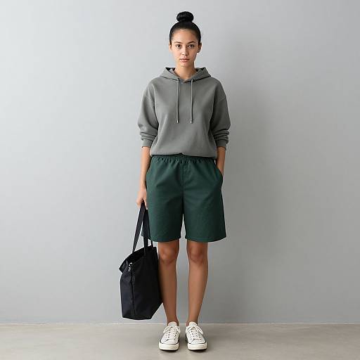 Young Woman in Casual Hoodie and Green Shorts Holding Black Tote Bag