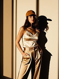 Stylish Woman in Satin Outfit and Brown Cap with Dramatic Shadow