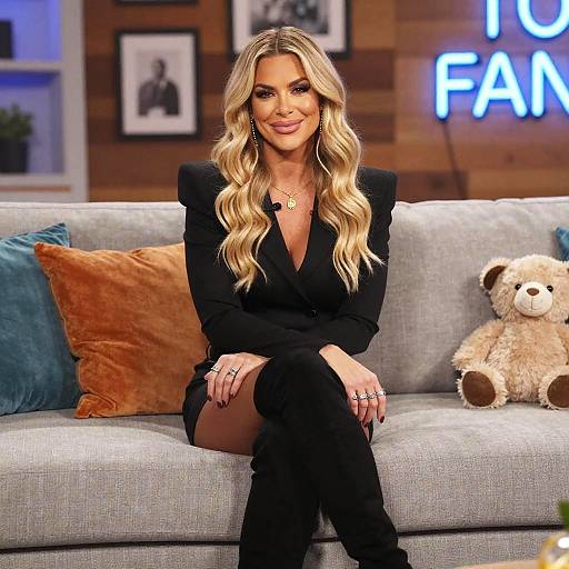 Blonde Woman in Black Outfit Sitting on Gray Sofa in Cozy Studio