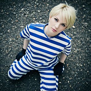 Young Woman in Blue and White Striped Outfit Sitting on Gravel Ground