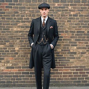 Stylish man in tailored three-piece suit against brick wall