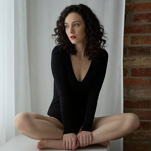 Contemplative Woman Sitting Cross-Legged in Black Bodysuit by Window