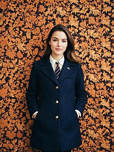 Preppy Fall Fashion Woman in Navy Coat Against Autumn Leaves Wall
