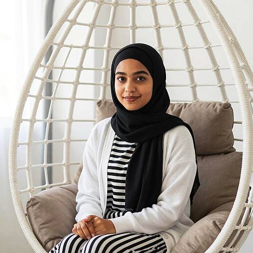 Young Woman in Black Hijab Sitting in White Woven Hanging Chair
