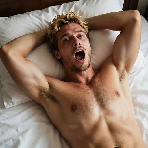 Young Shirtless Man Stretching and Yawning in Bed
