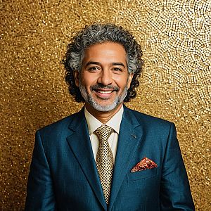 Smiling Middle-Aged Man in Blue Suit with Gold Tie on Textured Golden Background