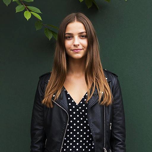 Young Woman in Black Leather Jacket and Polka Dot Dress Against Green Background