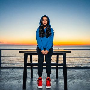 Woman in Blue Hoodie by the Sea at Sunset