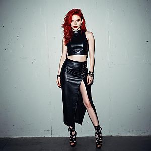 Stylish Red-Haired Woman in Black Leather Outfit with High Slit Skirt