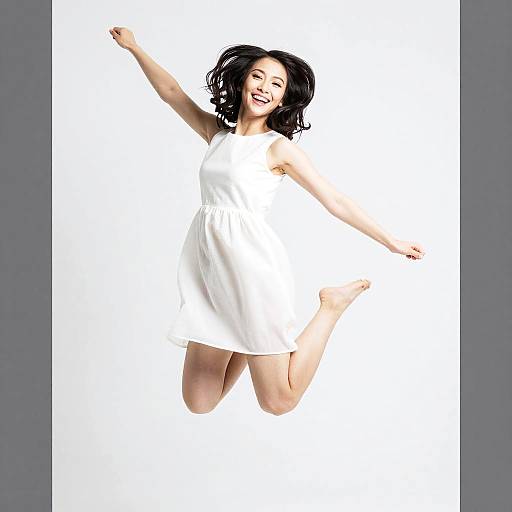 Happy Young Woman Jumping in White Dress - Energetic Gen Z Lifestyle