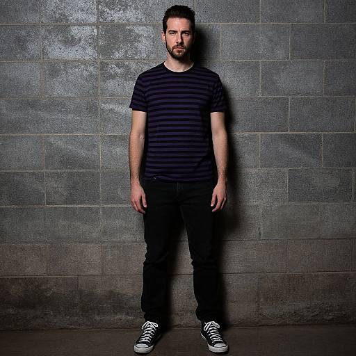 Man in Striped T-Shirt Standing Against Gray Brick Wall