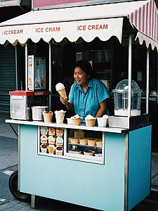 Street Ice Cream Vendor Woman Serving Cone at Colorful Cart