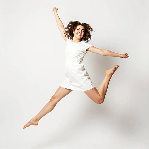 Energetic Young Woman Jumping in White Dress on White Background