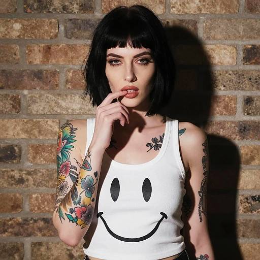 Tattooed Woman Wearing Smiley Face Tank Top Against Brick Wall