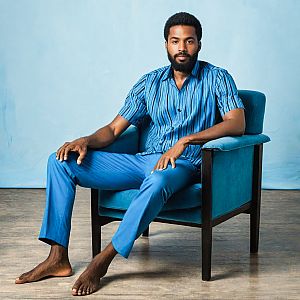 Barefoot man in blue attire sitting in armchair
