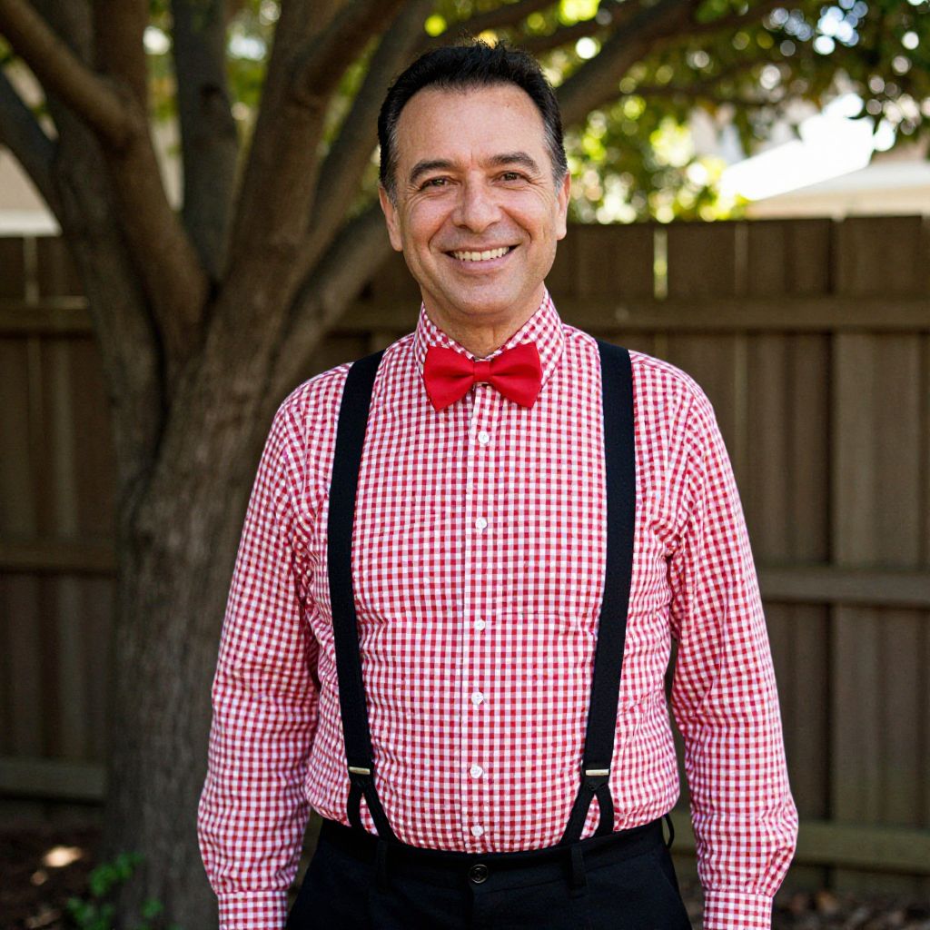 Smiling Man Wearing Red Checkered Shirt, Black Suspenders, and Bow Tie Outdoors