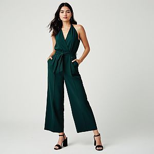 Woman Wearing Minimalist Chic Dark Green Halter Neck Jumpsuit with Deep V Neckline