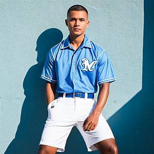 Confident Young Man in Blue Shirt Against Light Blue Wall