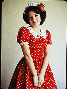 Young Woman in Vintage Red Polka Dot Dress with Strawberry Accessory