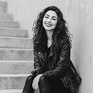 Woman with curly hair in leather jacket on stairs