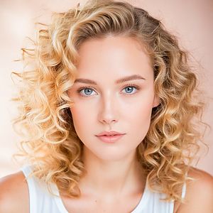 Close-up portrait of a woman with curly blonde hair and blue eyes