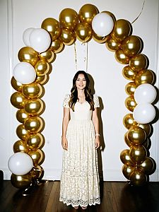 Elegant Woman Standing Under Gold and White Balloon Arch