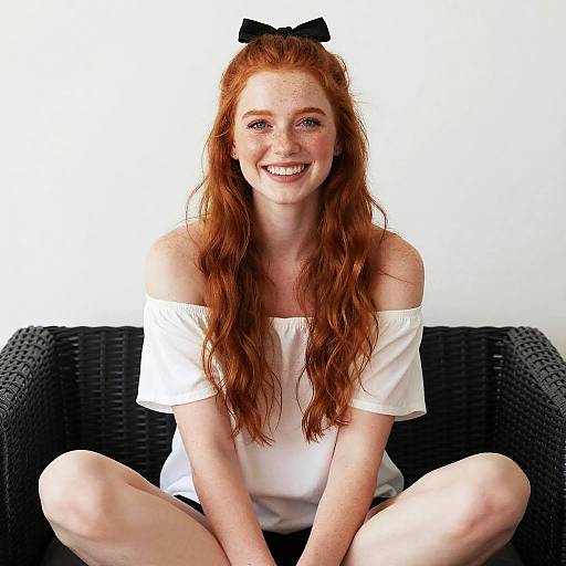 Smiling Red-Haired Woman Sitting Cross-Legged in Casual White Top