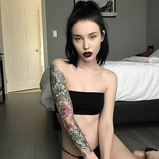 Confident Woman with Floral Sleeve Tattoo in Minimalist Bedroom