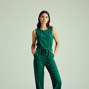 Woman in Stylish Green Sleeveless Jumpsuit Against Light Background