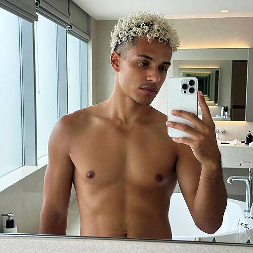 Gen Z Young Man Taking Shirtless Mirror Selfie with Curly Bleached Hair