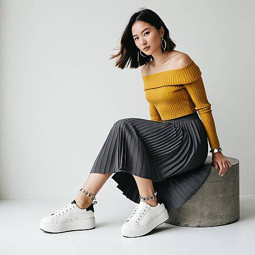 Stylish Woman in Mustard Off-Shoulder Top and Pleated Skirt Seated on Concrete Stool