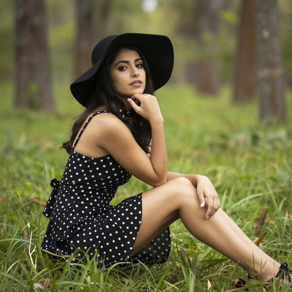 Young Woman in Polka Dot Dress and Black Sunhat Sitting Outdoors